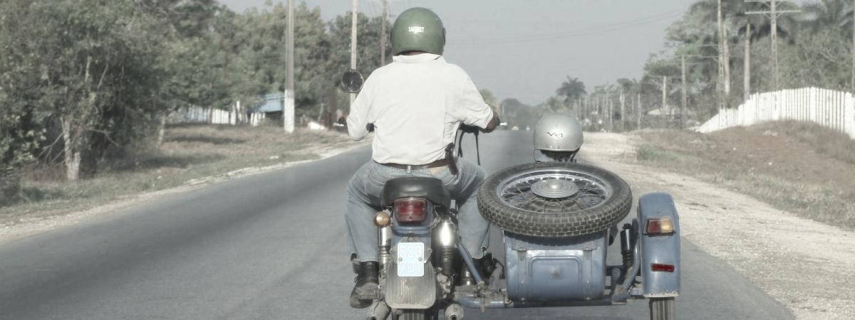 Ein älteres Motorrad mit einem Beiwagen fährt auf einer Straße